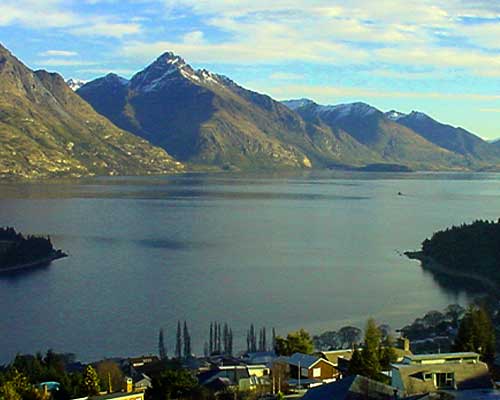 a photo of some lakeside houses with some sounds and mountains in the background.